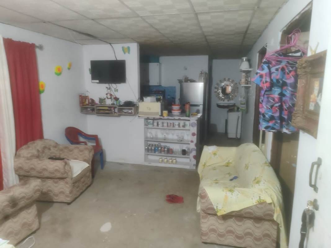 Simple living room with wall TV sofa chairs red curtains and kitchen in background Tocumen Panama