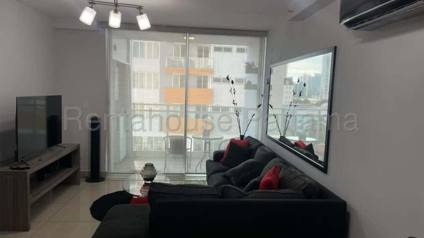 Living room with black sofa, glass doors opening to balcony with city view at PH Red Point San Francisco