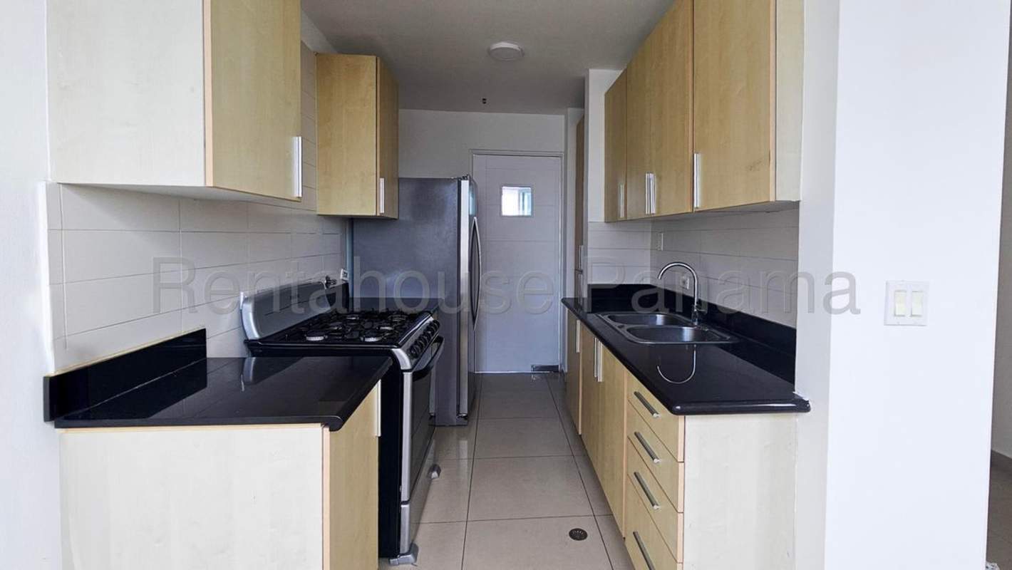 Apartment kitchen with black granite counters, wood cabinets, stainless steel appliances in Costa del Este Panama