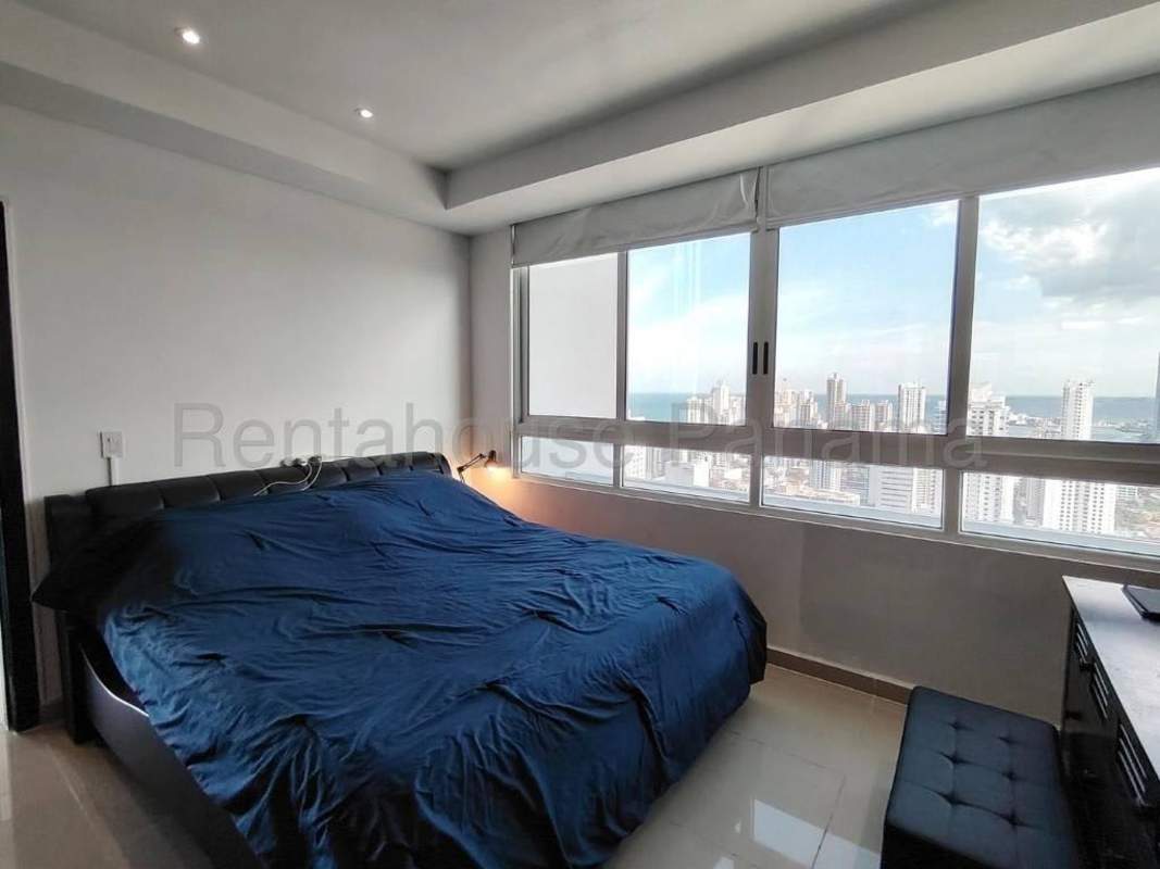 Modern bedroom featuring panoramic windows with ocean and skyline views in PH Quadrat San Francisco Panama