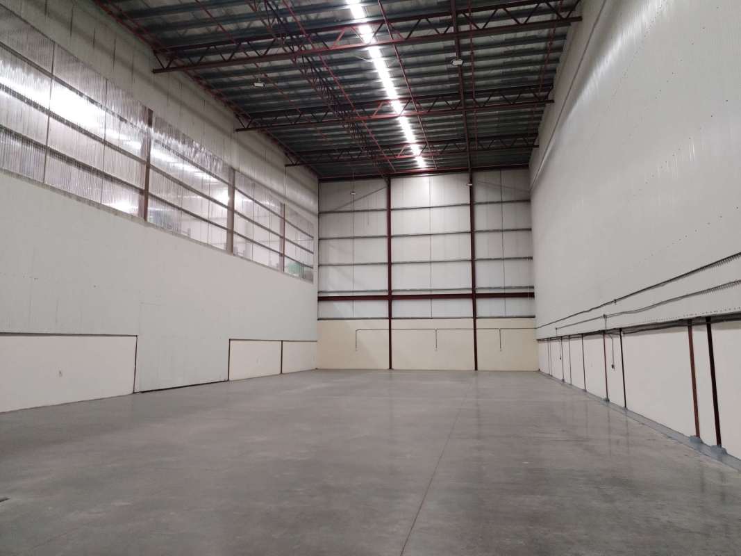 Modern office space with glass wall, ceiling tiles inside industrial warehouse in Panama