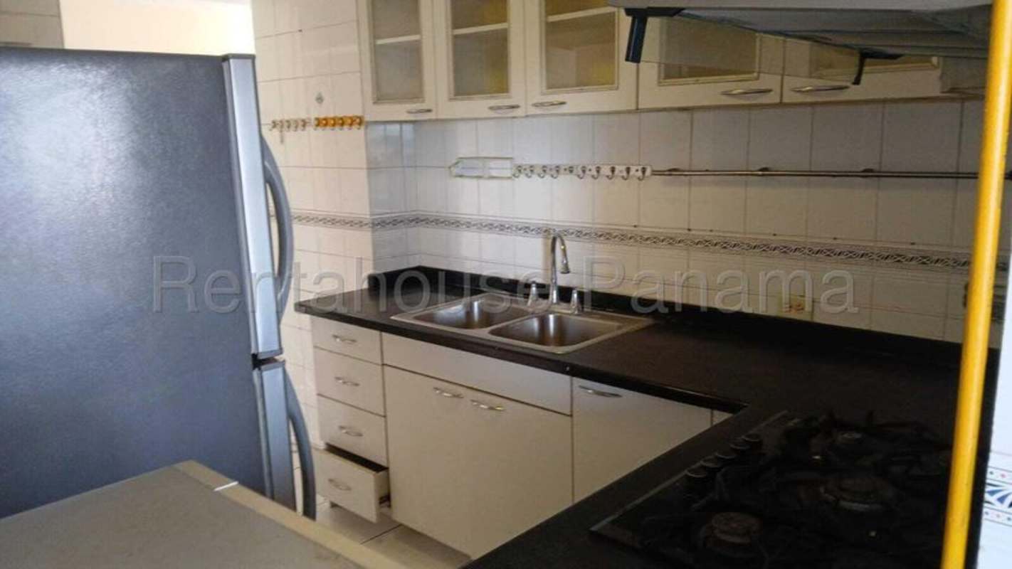 Functional kitchen with white cabinets, black counters, refrigerator and stove at PH El Cangrejo for rent in Panama City