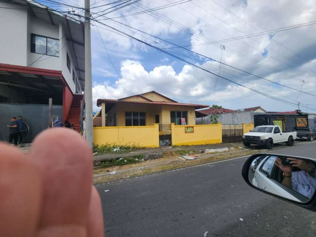 Single-story yellow commercial house with fenced yard and signage for rent in Panama City