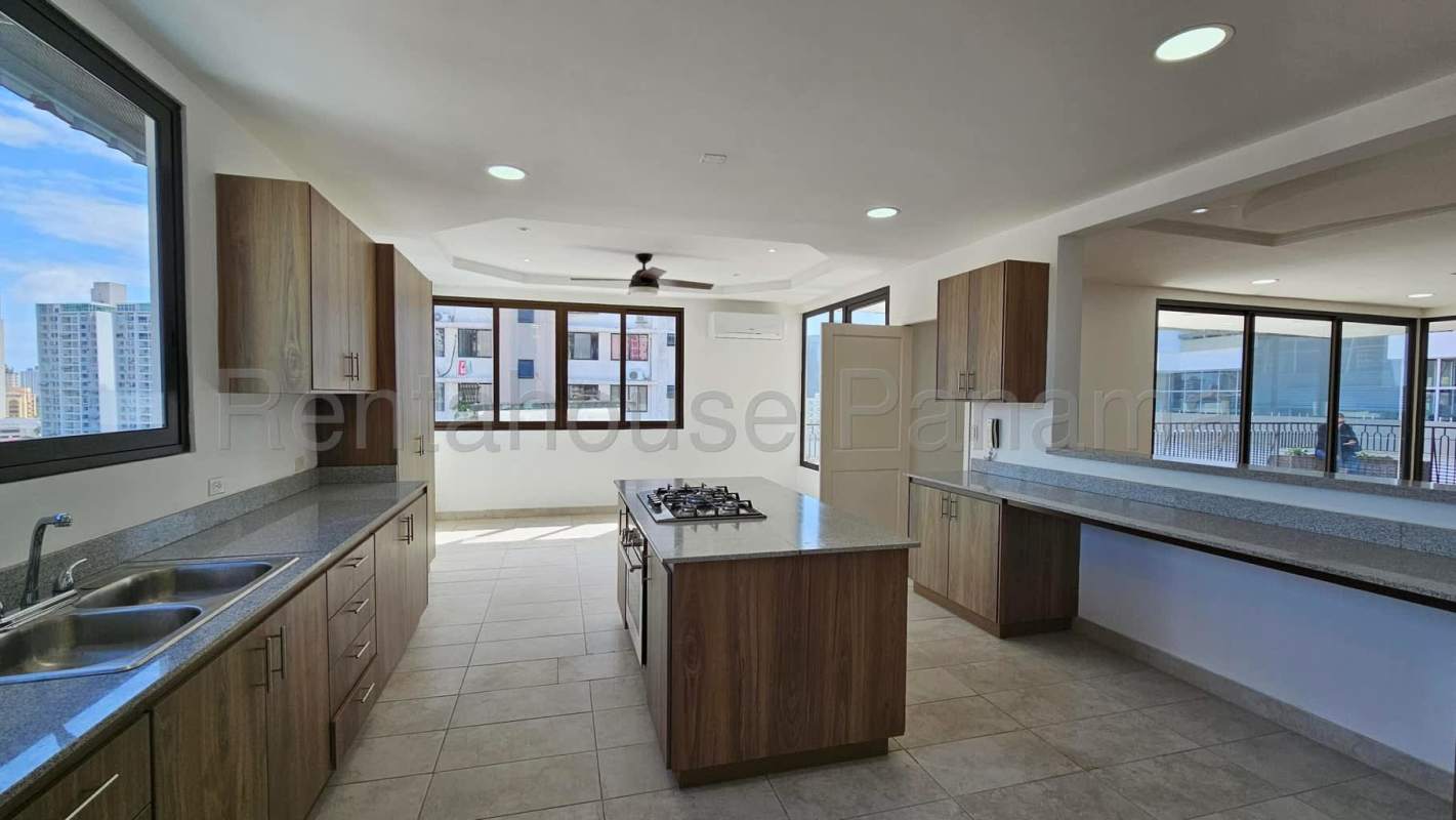 Spacious kitchen with granite counters, island cooktop, and wood cabinetry PH Setton Place El Cangrejo