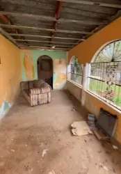 Enclosed porch with arched barred windows peeling paint sofa in rental house Burunga Panama