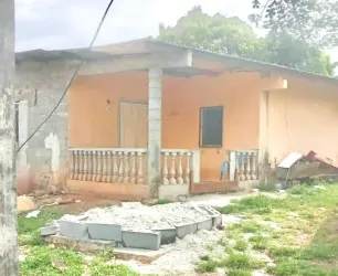 Small house peach facade porch concrete columns grass yard construction debris Burunga Panama