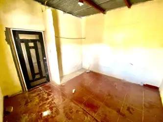 Empty room beige walls tile floor exposed ceiling black metal door Burunga house Panama