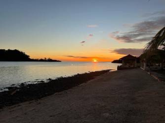 Open beachfront lawn with palm trees waterfront view and sunset Portobelo Panama