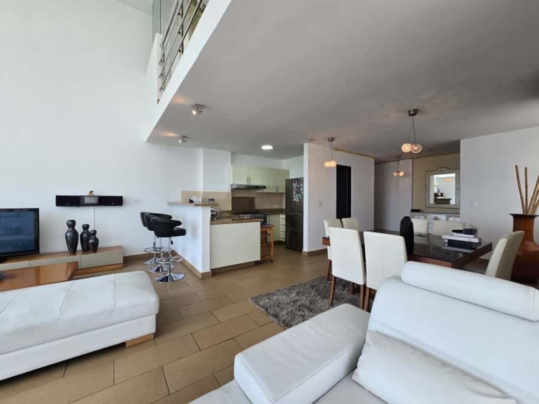 Modern double-height living and dining area with loft and city views at PH El Cangrejo Loft Panama