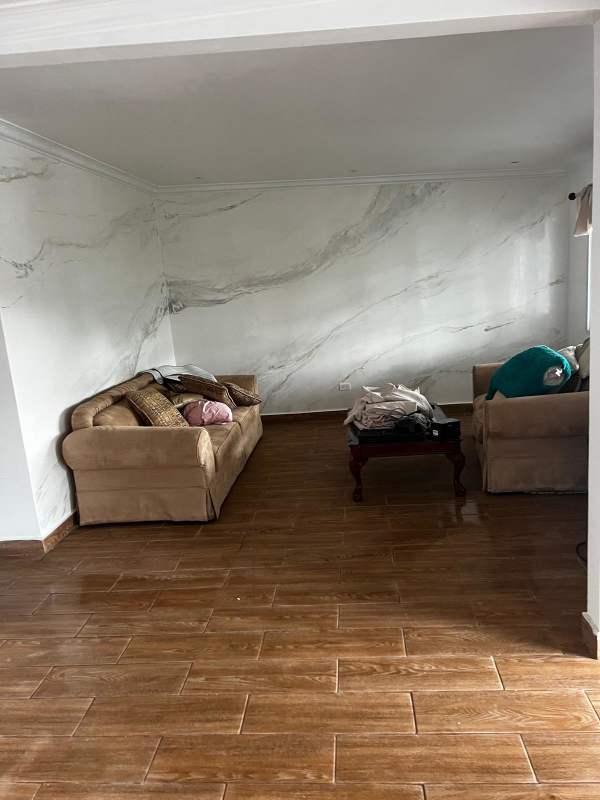 Living room with marble-style accent wall, beige sofas, wooden coffee table, at Betania house for rent Panama City