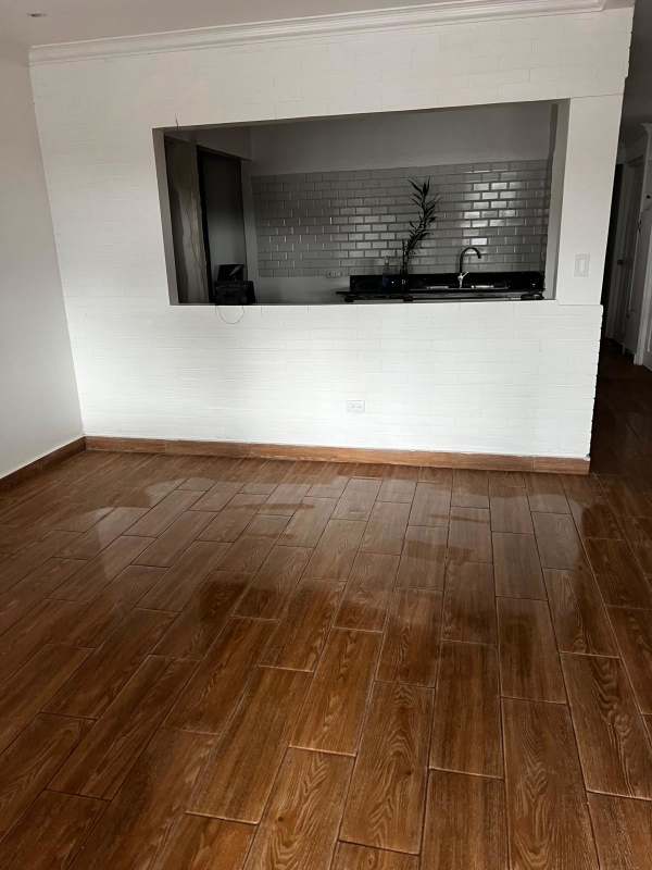 Minimalist living space with wood-look tile flooring, white walls at Betania house for rent Panama