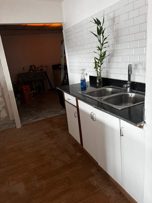 Rustic bathroom with stone wall, pedestal sink, and toilet in Betania house Panama