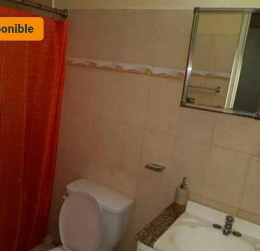 Bathroom with granite sink countertop, beige tiles, shower and orange curtain at Campo Limberg Panama