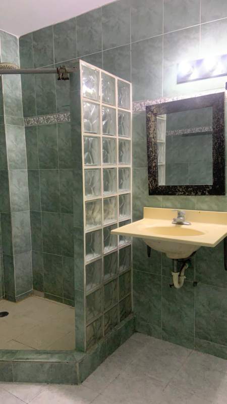 Bathroom with green tile, pedestal sink, and glass block shower divider Obarrio Panama