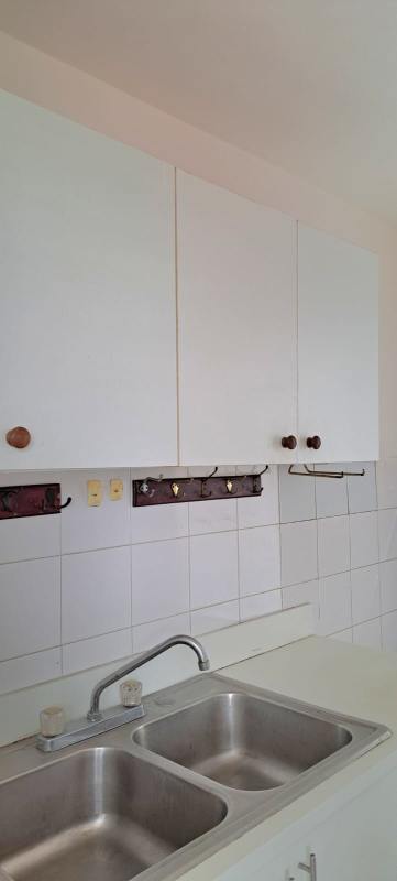 Minimalist kitchen with white cabinets, double stainless-steel sink and white tiled backsplash at PH Torres del Sol I