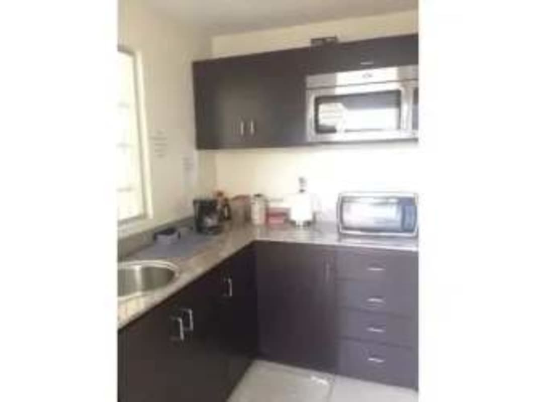 Small office kitchen area with microwave, dark cabinets, window at PH Plaza Hato Pintado