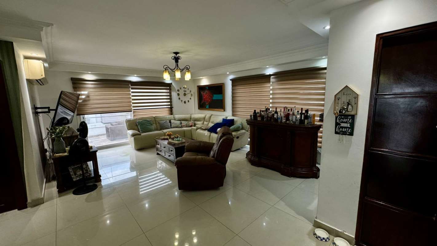 Contemporary living room with sectional, bar, TV, cream tiles Altos del Golf residence Panama