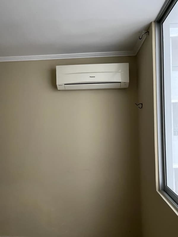 Apartment bedroom with wall AC, large window, beige colors, and city view Panama City