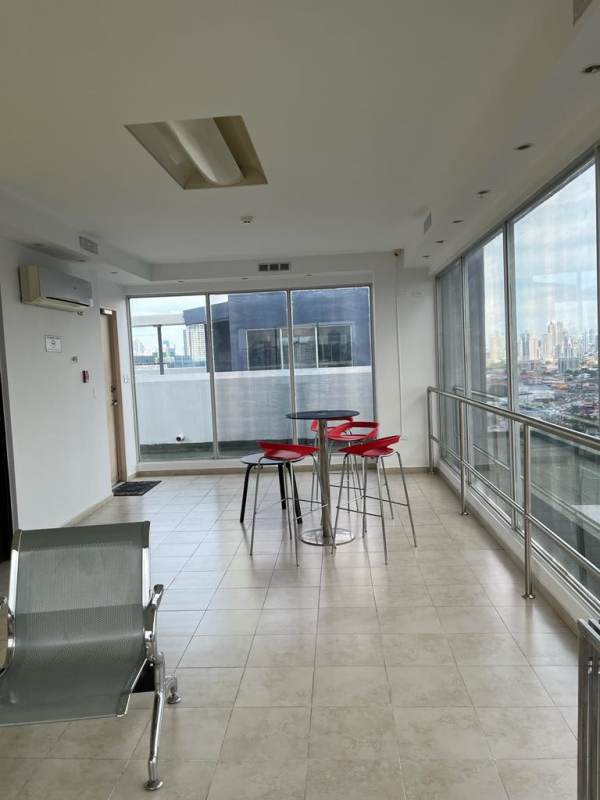 Sunroom/lounge with floor to ceiling windows, red stools, city skyline in apartment rental Panama