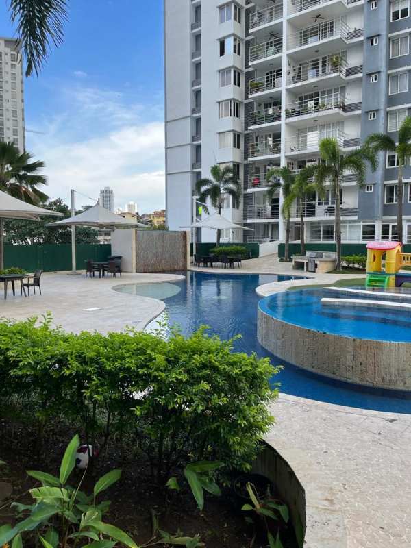 Modern apartment complex pool with palm trees, lounging area and playground in Panama City