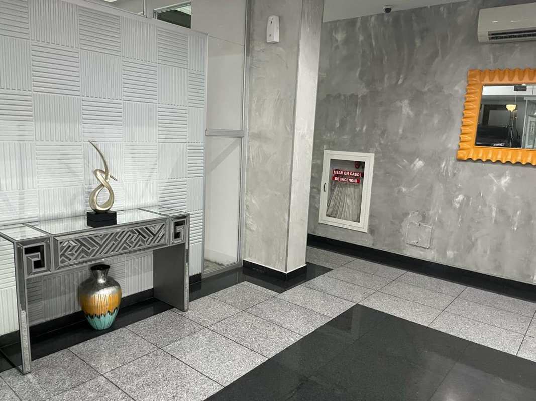 Modern apartment lobby with decorative wall, console table and orange framed mirror Panama rental