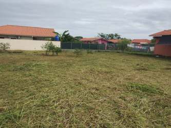 Vacant fenced grassy lot in suburban area with red roof houses in Monagrillo Chitré Panama
