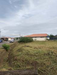 Vacant corner lot with grass, paved access and homes around in Monagrillo Chitré Panama
