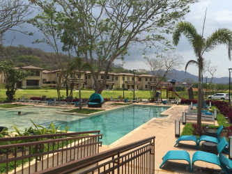 Beautiful swimming pool with lounge chairs and mountain views at River Valley Panama Pacifico