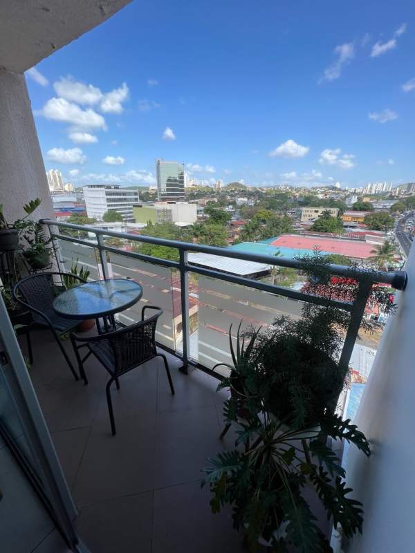 Modern balcony with glass railing, furniture and city skyline view at PH Vista Hermosa Panama City
