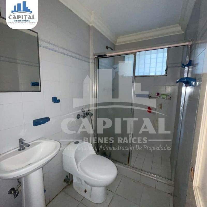 Modern bathroom with glass shower, blue accents, pedestal sink in Betania house for sale Panama