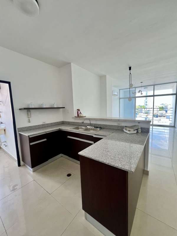 Open concept kitchen with granite counters, dark cabinetry, pendant lights in PH Famagosta Loft San Francisco Panama
