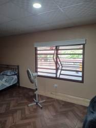 Bedroom with large louvered window, wood floor and fan in house Nuevo Emperador Panama