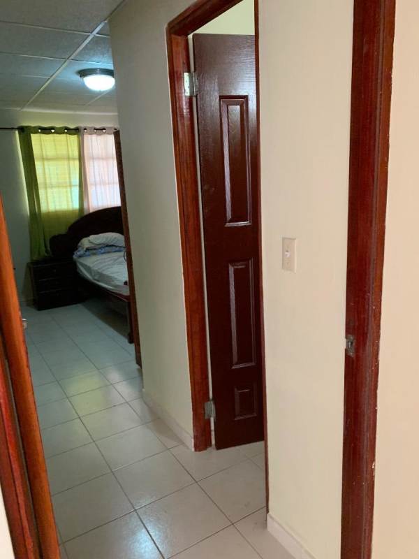 Interior hallway leading to bedroom spaces with tiled floor and wooden doors in Ciudad San Lorenzo