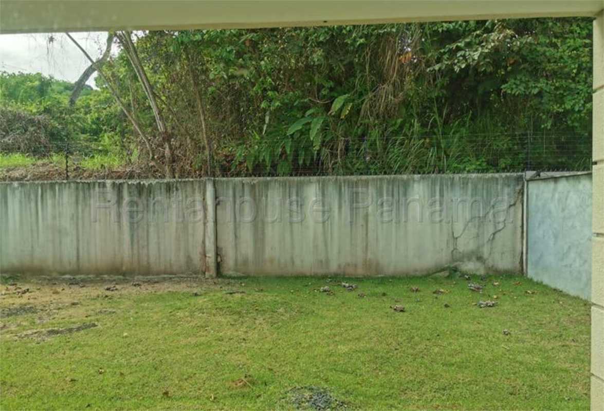 Private backyard green lawn enclosed with concrete wall and wire fencing Altos de Panamá