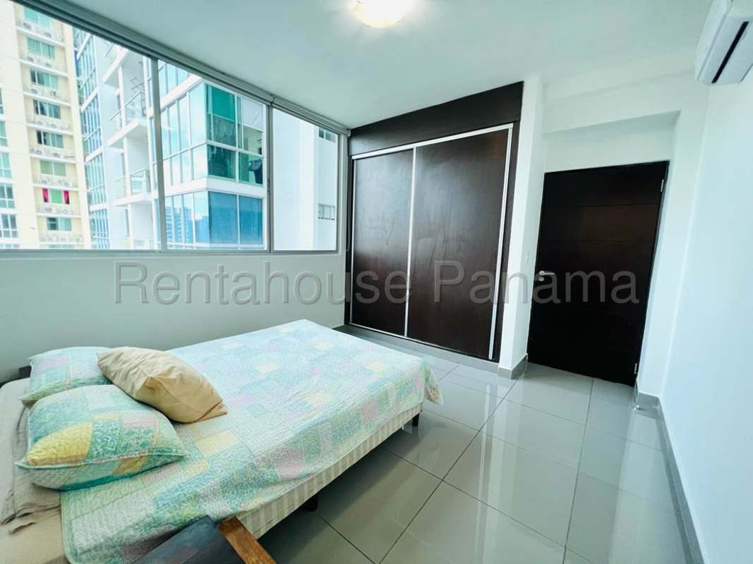 Bedroom with large built-in closet and city view window at PH Quartier 74 apartment Panama City
