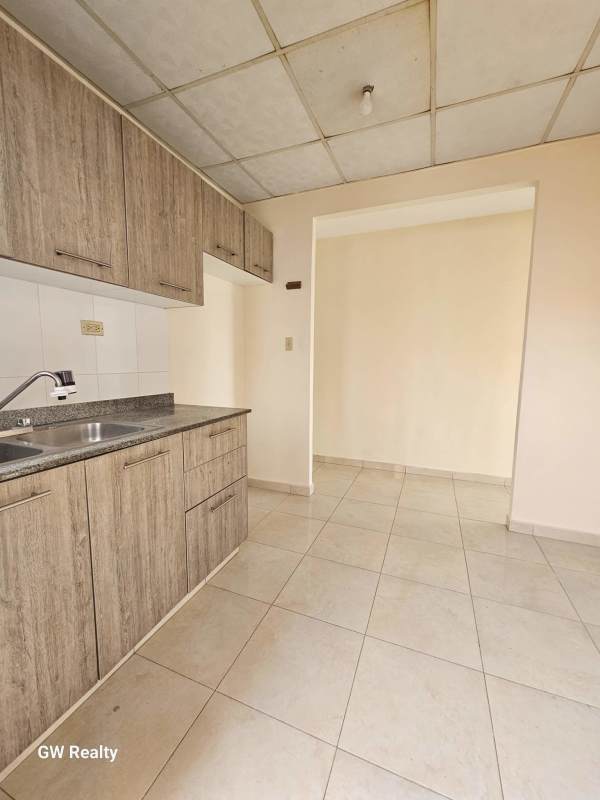 Modern kitchen with granite countertops, wood cabinets in Colinas del Lago house Panama