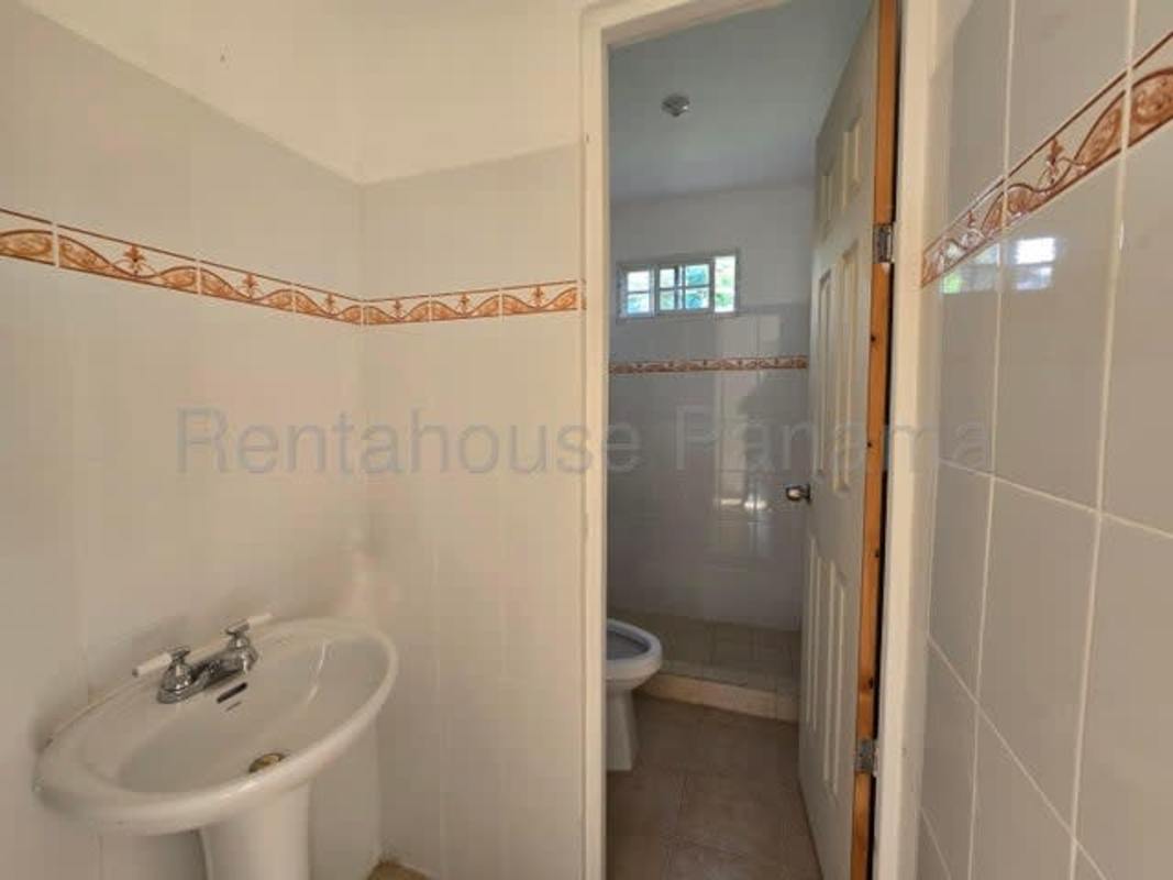 Bathroom with tiled walls, pedestal sink separate toilet area Pacora house