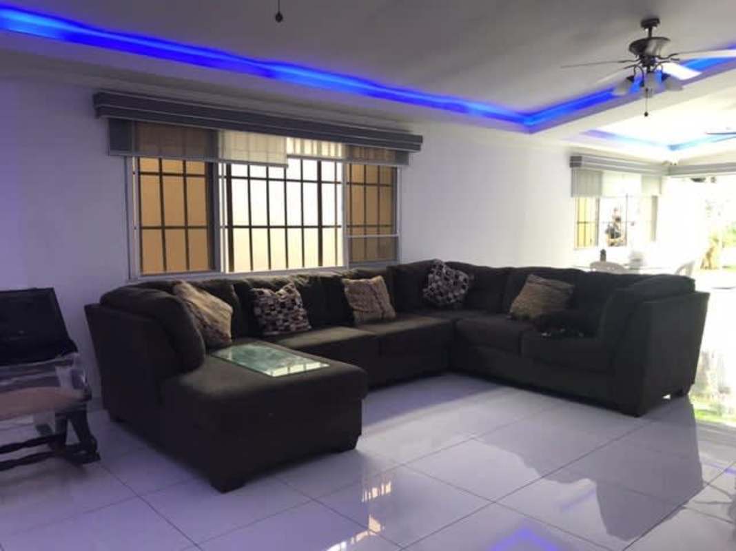 Bright living room with sectional sofa, LED lighting, white tile floors house in Panama