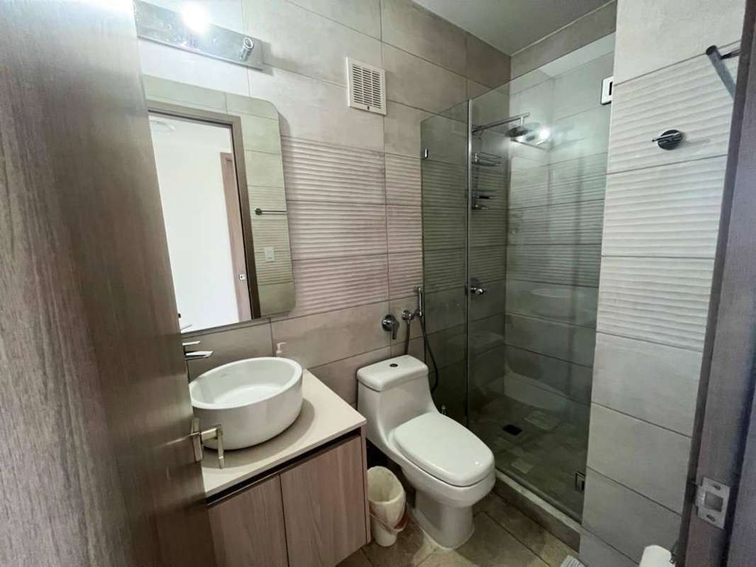 Bathroom with glass shower, vessel sink, and tile walls in PH Costanera Panama City
