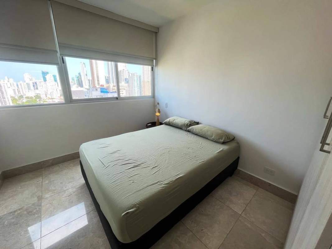 Furnished bedroom with large window and city skyline view in PH Costanera Panama