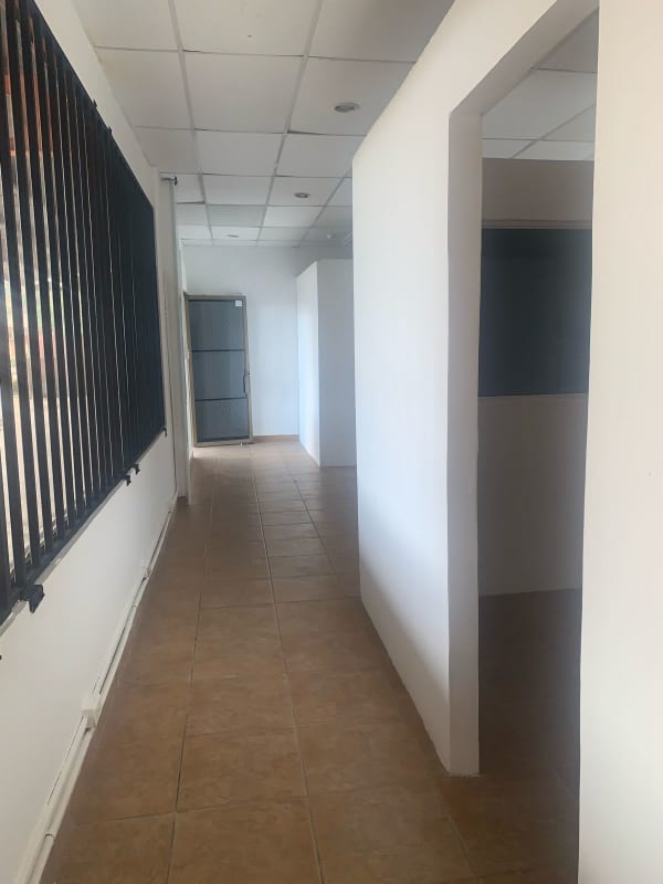 Exterior facade with large windows, security bars, red metal stairs, covered dock in Villa de las Fuentes