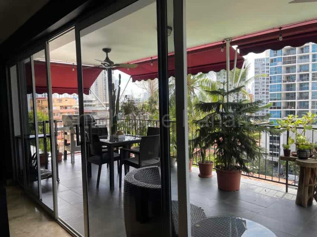 Covered balcony space with red awning, plants, skyline view El Cangrejo Panama