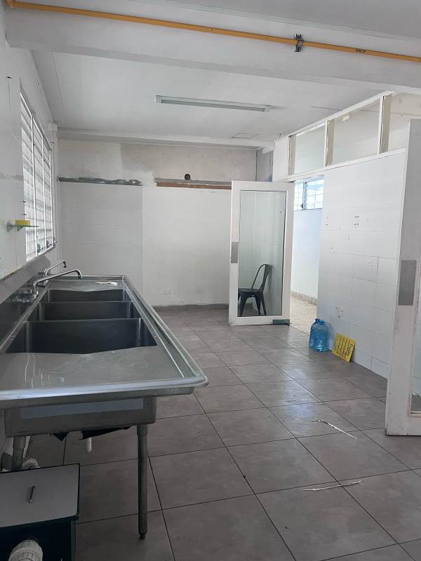 Large industrial kitchen area with triple sinks, tiled walls and floor, ready for food processing in Panama City