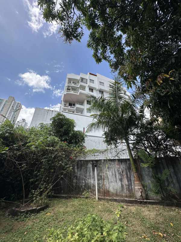 Modern white apartment building with balconies and gardens adjacent to available development lot in Parque Lefevre Panama