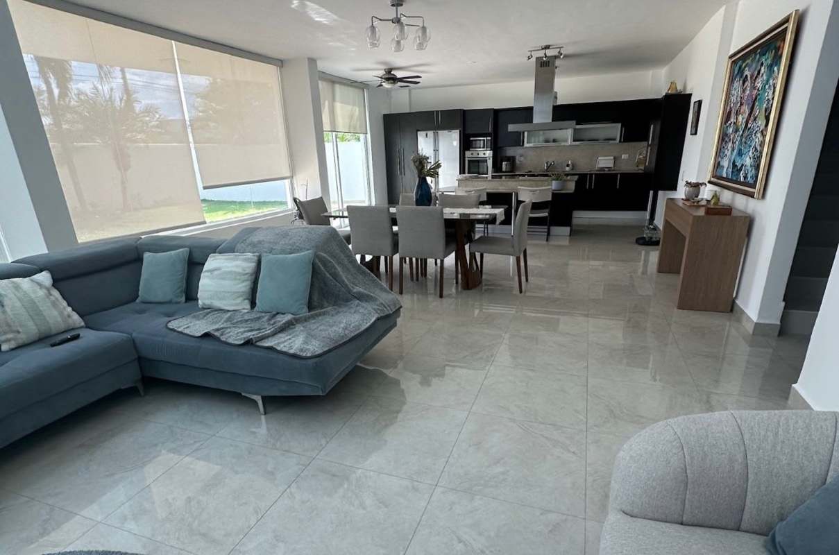 Open-concept living and kitchen area with window lighting Costa Sur home