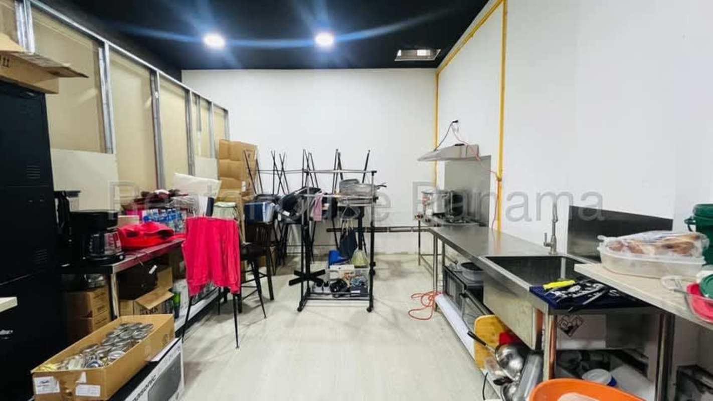 Industrial restaurant kitchen space with stainless steel countertops, sink, and shelving in Panama City