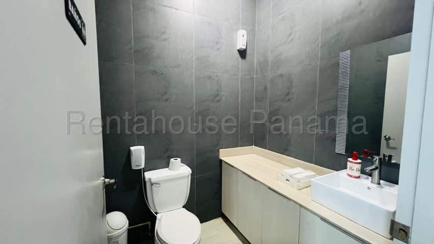Minimalist modern bathroom with dark tiles, large mirror, and toilet in San Francisco retail property