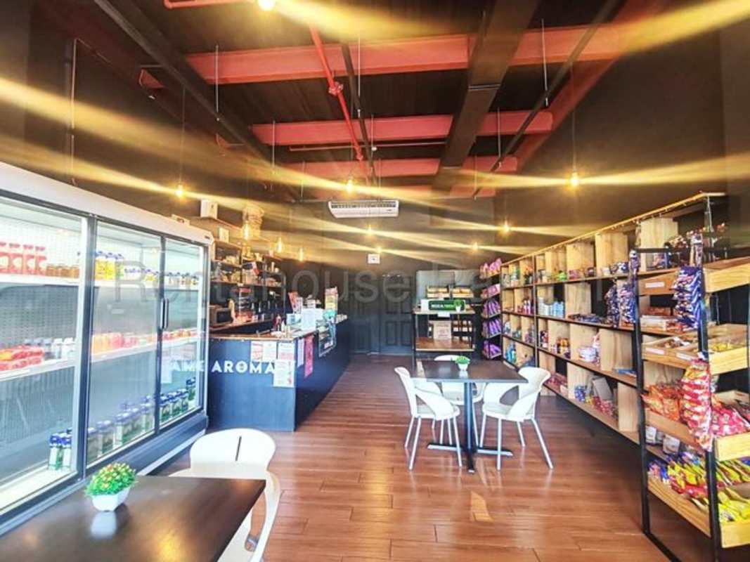 Shop interior with ceiling ductwork, display fridges, counter and pendant lights at Plaza El Cangrejo Panama