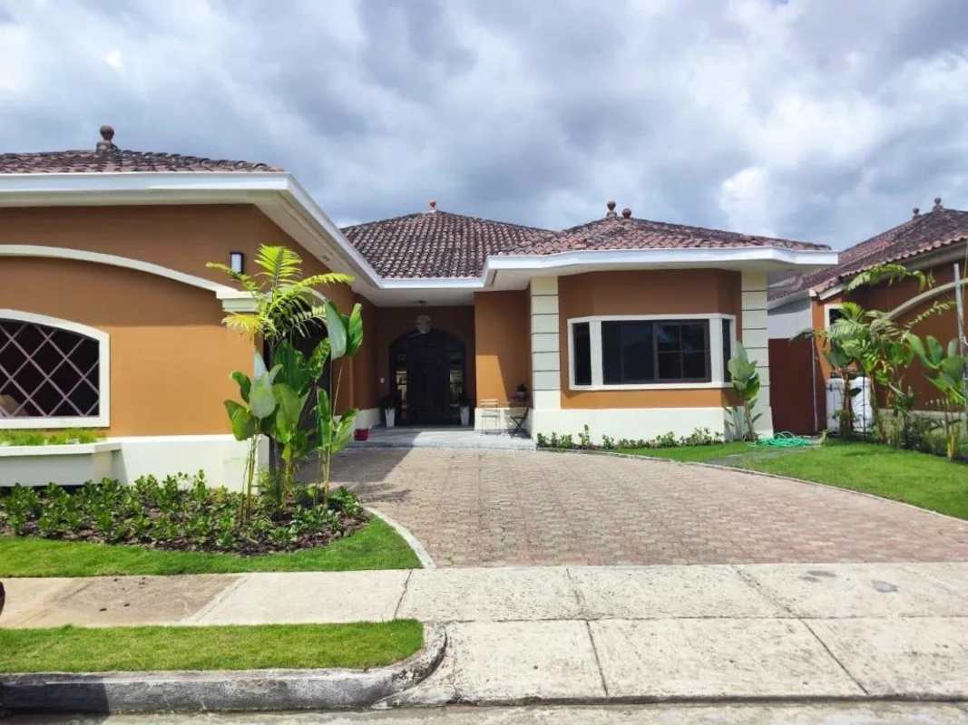 Mediterranean-style house facade with tile roof, arched windows and landscaped lawn Costa Sur Panama