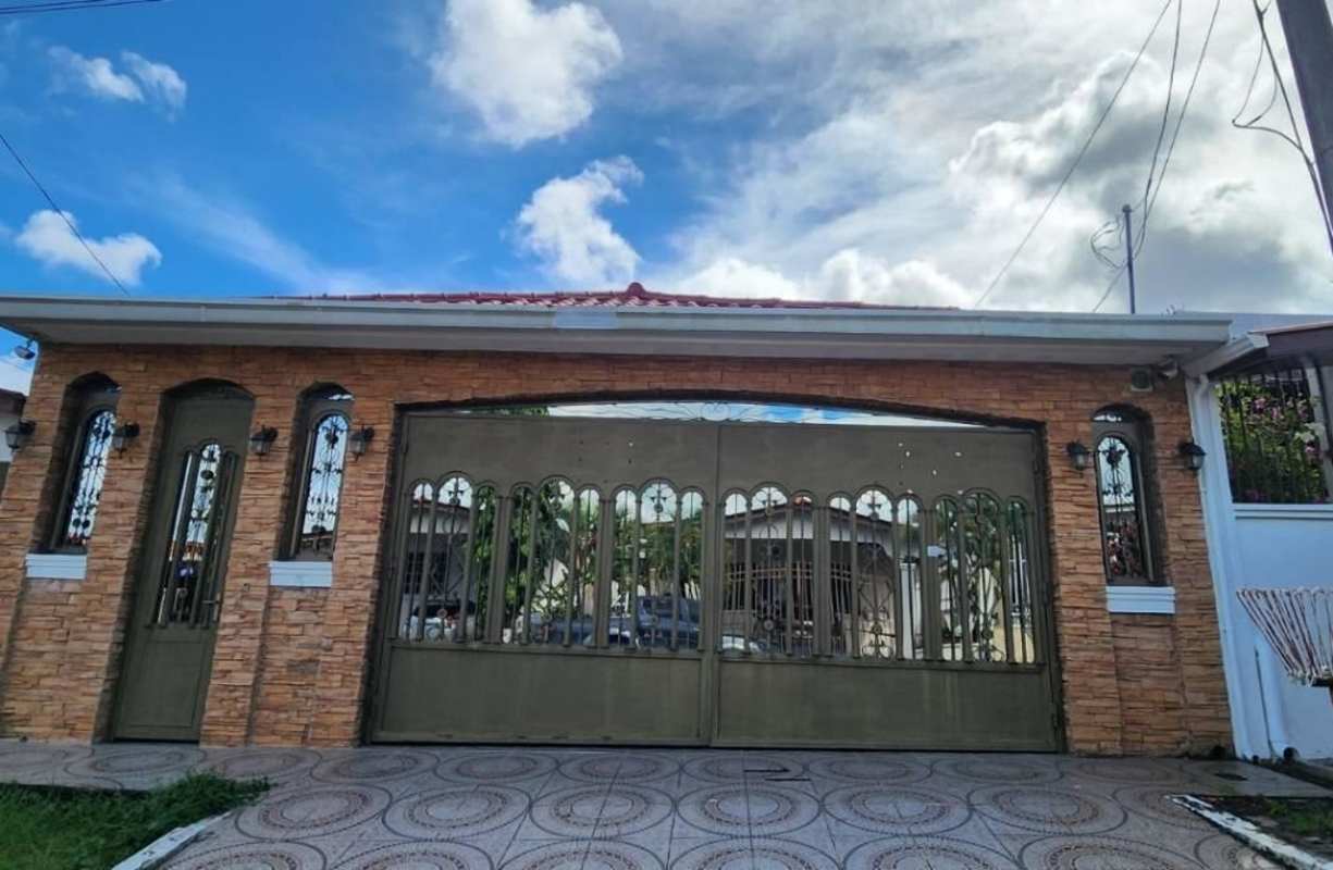 Gated Mediterranean-inspired home facade with metal gate, stone finish in Brisas del Golf Panama City